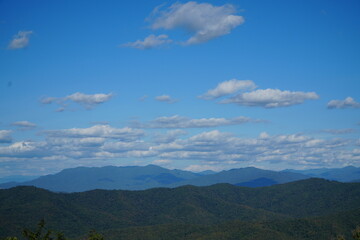 Mountain Range Under Clear Blue Sky with Soft Clouds