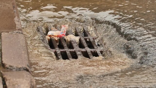 Rainwater runoff carrying urban waste flowing into a clogged storm drain