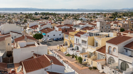 Angled aerial view of suburban homes with red roofs and scenic lagoon background