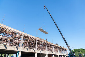 A crane lifting a concrete floor slab to the upper level of a building.