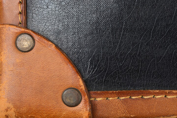 A close-up shot captures the corner detail of a vintage suitcase, showing a rounded brown leather...