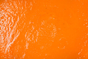 A full frame macro shot showcasing the vibrant orange color and thick smooth texture of freshly pureed carrot soup