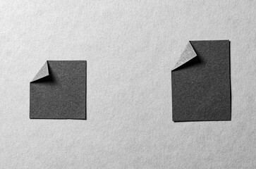 Pieces of black paper notes or sheets with folded edge dog-ear earmark and copy space for text on gray background, top view flat lay