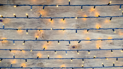 Warm Christmas fairy lights glowing on a rustic brown wooden background with copy space for text.