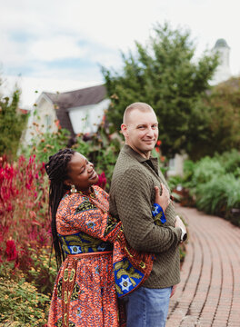 Smiling interracial couple embracing in a lush garden walkway