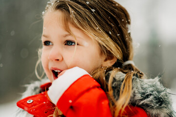 Close-up of girl in red coat with snowflakes in her hair