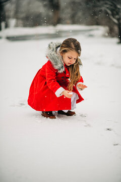 Young girl playing with snow during winter