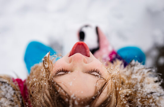 Young girl looking up catching snow on her tongue