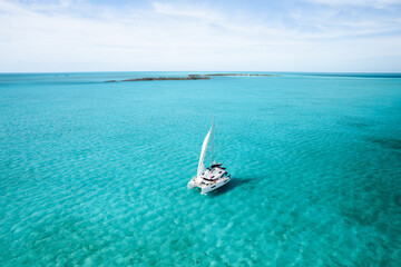 Aerial view of a catamaran sailing in shallow turquoise water
