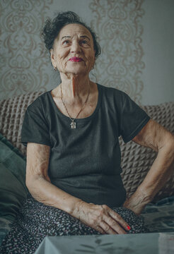 An elderly woman sits with a smile inside