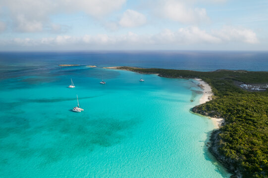Aerial view of sailboats anchored in turquoise water near island