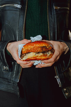 Girl in a black leather jacket holding a burger