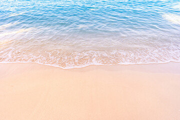 Soft blue ocean waves gently lapping onto a pristine tropical sandy beach