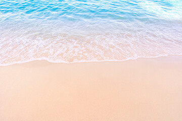 Soft blue ocean waves gently lapping onto a pristine tropical sandy beach