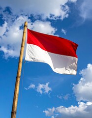 Indonesian Flag Waves Against Blue Sky and Clouds