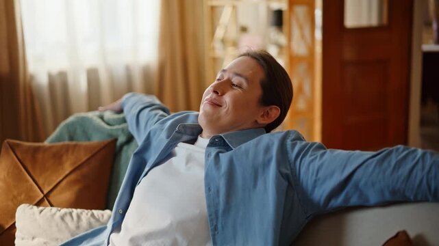 Closeup guy falling couch feeling happy at home. Lazy man taking rest chilling