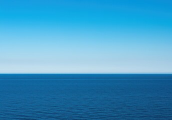 Fototapeta premium The vast open ocean meeting the clear blue sky along a perfectly straight, undisturbed natural horizon line at midday, background, cloudless, sunshine