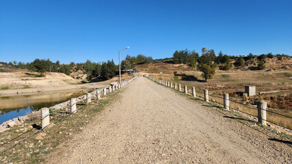 Causeway crossing a water reservoir bordered with the concrete post fencing with steel cables