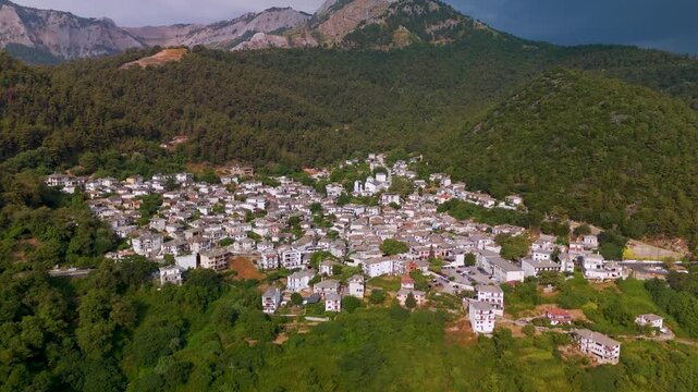 Aerial drone approach shot revealing the picturesque Panagia village nestled on the forested eastern slopes of Mount Ipsarion, Thasos Island, Greece.
