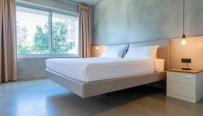 Modern minimalist bedroom with a floating bed, concrete walls, and a large window overlooking greenery.