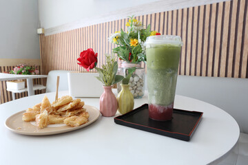 Thai crispy roti pancake with sweetened condensed milk and  iced matcha strawberry in a modern cafe setting