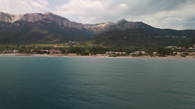 Aerial drone pan over the turquoise bay of Golden Beach approaching the forested slopes of Mount Ipsarion, Thasos Island, Greece.