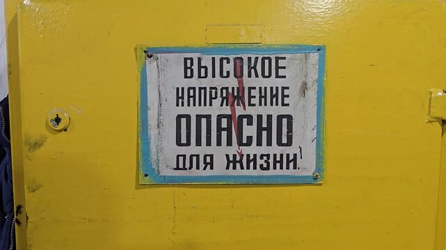 Slow camera zoom in on an electrical panel with a warning sign reading "High Voltage. Danger to Life."
