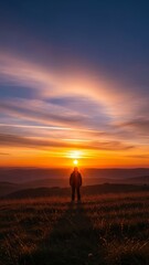 Silhouetted Figure Against Vibrant Sunset Over Scenic Landscape