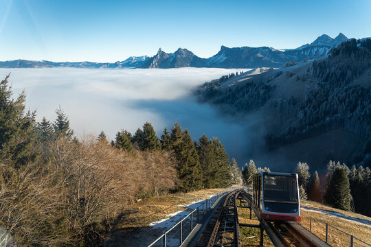 Funiculaire alpin sortant du brouillard avec les montagnes et les sapins