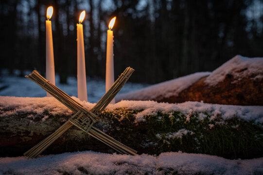 Blessed Imbolc greeting card. Brigid cross of straw and candles. Winter forest nature background. symbol of Imbolc