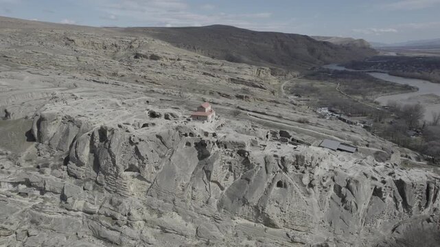 Aerial drone view of the Uplistsuli Church of the Prince in Uplistsikhe, Georgia, captured from a moderate height, revealing rock-hewn stone architecture within the ancient cave town near Gori.