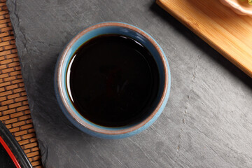 Dark soya sauce in blue ceramic dish on dark slate background