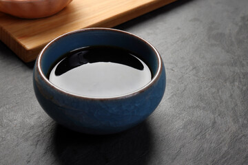 Dark soya sauce in blue ceramic dish on dark slate background
