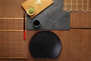 wasabi sushi soya sauce in a small dishes plate, featuring a vibrant green color  texture on dark slate wooden board bed bamboo mat copy text space
