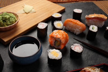High-quality close-up of fresh assortment sushi rolls served on a dark plate, featuring vibrant colors, fresh fish, laid on slate board bamboo mat chopsticks