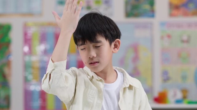 Tired Schoolboy Holding Head in Classroom, Feeling Stressed