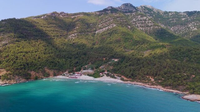 Aerial drone shot starting high and gliding down to approach the vibrant turquoise waters of Paradise Beach near Kinira, Thasos, Greece.