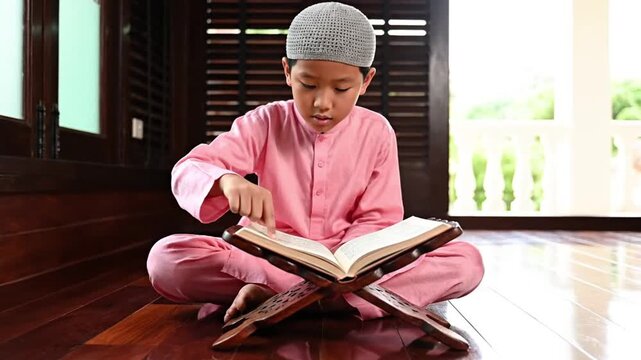 Young Muslim Boy in Traditional Attire Reading Holy Book on Rehal, Focused on Islamic Education and Cultural Devotion at Home