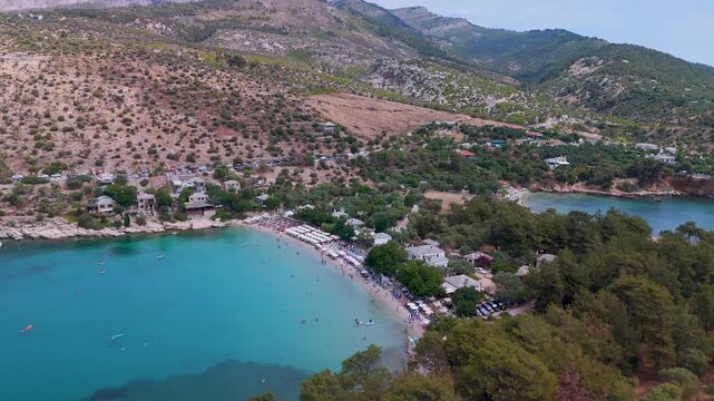 Scenic aerial drone view panning over the picturesque coves and beach of Alyki Peninsula, Thasos, Greece, highlighting the turquoise Aegean Sea and lush coastal forest.