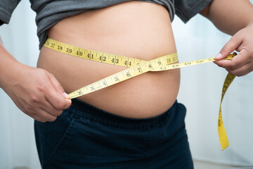 Asian woman with fat belly big size overweight and obesity with measure tape.