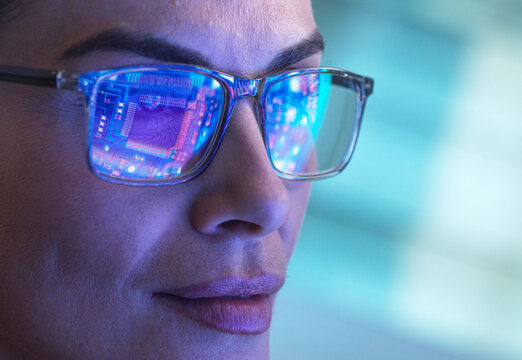 Engineer wearing glasses with computer chip reflections in a hi-tech setting