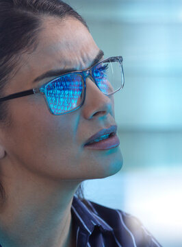 Concerned woman with binary code reflection in glasses facing cyber attack