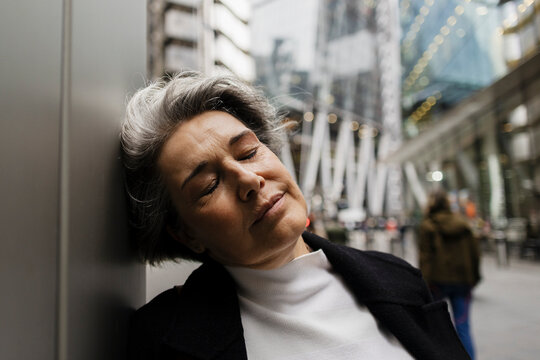 Exhausted woman resting on city street showing burnout and stress