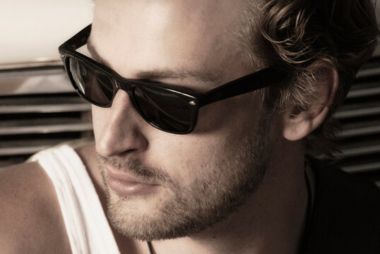 Man with sunglasses looking away in sunlight wearing a tank top