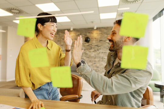 Two colleagues in a modern office celebrating success with a high five