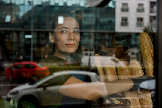 Saleswoman working in bakery arranging bread behind window display