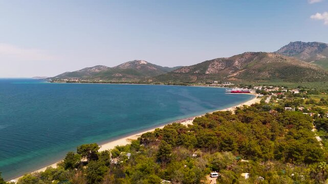 Aerial Drone Panning Shot Revealing the White Sand Beach, Lush Green Forest, and Turquoise Thracian Sea at Prinos Port, Thasos Island, Greece.