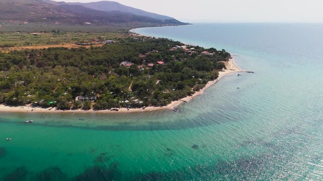 Aerial Drone Descending Shot Over Lush Green Forest Towards Prinos Beach, Thasos, Greece, Featuring White Sand and Turquoise Thracian Sea.