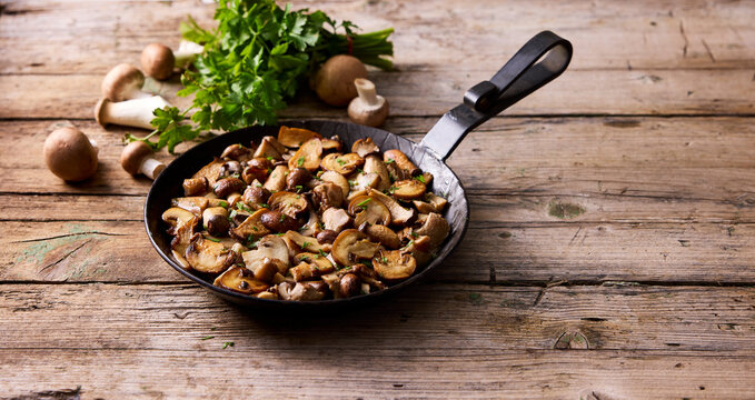 Saut�ed mushrooms and parsley in pan on rustic wooden table