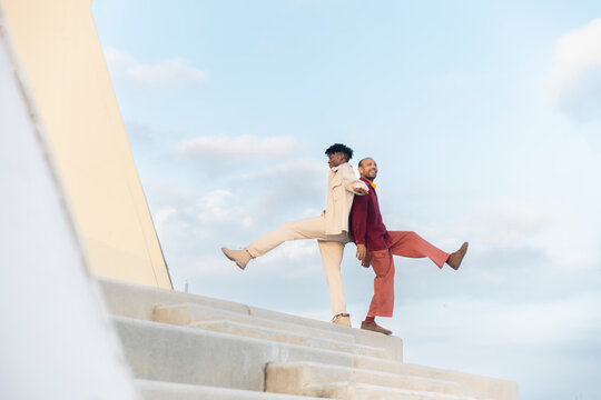 Two adults dancing and laughing on urban steps expressing joy and freedom